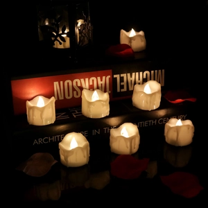 Detail view of flickering warm yellow LED tea lights with dripping wax effect on table