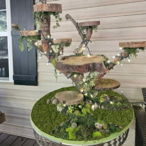 Detailed view of artificial moss on multi-layered wooden stand with LED string lights