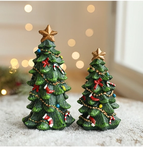 Detailed macro view of two green resin Christmas trees with gold stars and festive ornaments