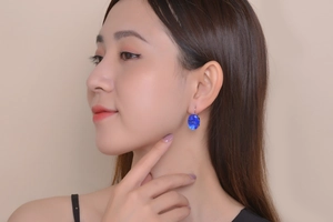Close-up of model wearing elegant oval blue gemstone earrings with silver setting