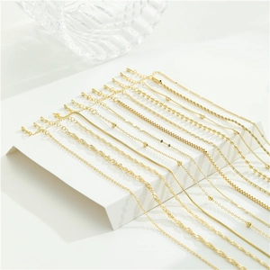 Collection of gold stainless steel necklace chains in various styles on a minimalist display