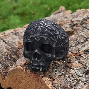 Vintage oversized skull ring with intricate silver-toned carvings on a wood log