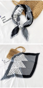 Detail of pleated black and white square scarf with geometric patterns and ripple textures