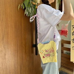 Détail du mini sac en tissu oxford jaune avec cœurs et bandoulière tressée