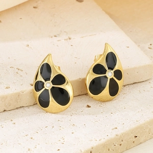 Detailed macro view of 18K gold petal earrings with black enamel and tiny center zircon