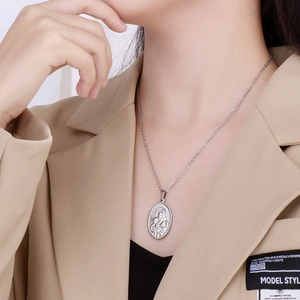 Macro view of silver stainless steel oval medallion necklace featuring Virgin and Child