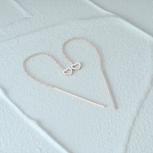 Creative overhead view of S925 sterling silver heart tassel chain earrings on stone