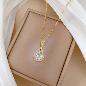 Macro shot of gold teardrop necklace with micro-pave crystals on a jewelry box