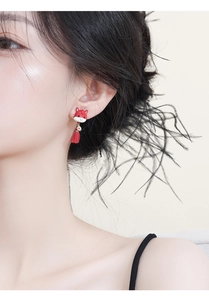 Close-up of red animal stud earrings with elegant tassels on a model for a festive look