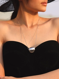 Polished silver bean pendant necklace on model with elegant summer outfit detail