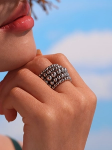 Detail of layered silver bead ring with metallic mirror finish against a blue sky background