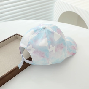 Dettaglio del cappellino tie-dye blu e rosa con farfalla bianca e cinturino in velcro