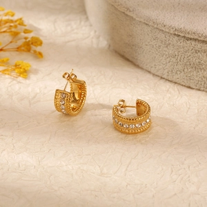 Detail of gold-plated hoop earrings with sparkling crystals and twisted edge texture