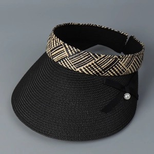 Détail d'une visière en paille noire avec nœud élégant et perle sur bandeau géométrique
