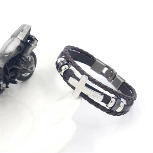 Detail of men's layered brown leather bracelet with silver cross and metal beads