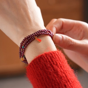 Detail of garnet wrap bracelet with golden gourd charm and blue lapis accents