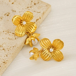 Elegant gold flower pearl earrings in stainless steel on a textured stone background