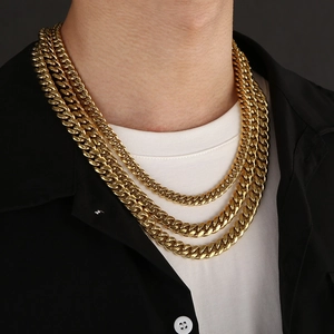 Close-up of three layered gold Cuban link chains on a male model wearing a black shirt