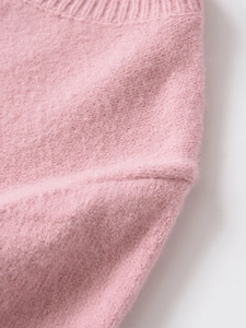 Detail of pink knitted sweater showing ribbed neckline and fine stitching texture