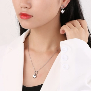 Close-up of model wearing silver 3D heart pendant necklace and earrings set