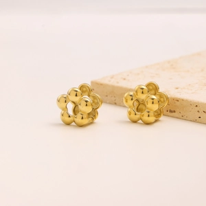 Detailed macro view of golden flower earrings with five petals on a textured stone base