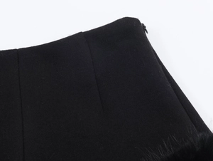Nahaufnahme des verdeckten Reißverschlusses und Federbesatzes an schwarzen Hotpants