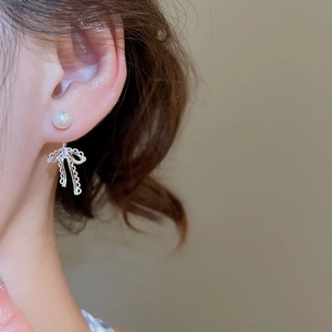 Macro view of lace style hollow bow pendant earrings with white pearl detail on model