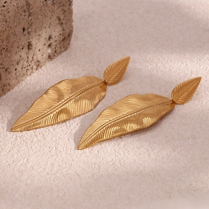 Detailed macro view of gold-plated feather leaf earrings with fine texture on stone