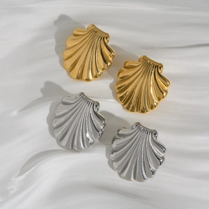 Minimalist gold and silver seashell earrings on white silk fabric for a vacation look