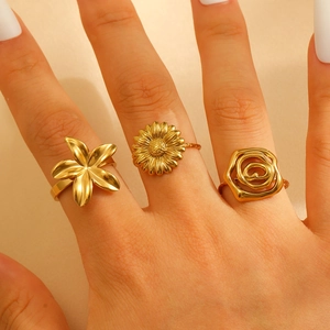 Three-piece gold-plated ring set with floral, daisy and rose designs on a model hand