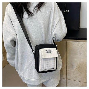Détail d'un sac bandoulière en toile noir et blanc porté par un mannequin pour le quotidien