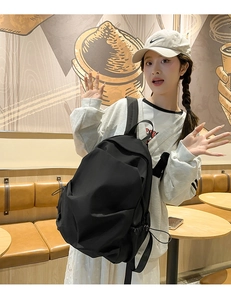 Detail of adjustable drawstring side pocket on casual black nylon backpack in cafe setting