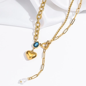 Macro shot of gold double-layer necklace with blue teardrop zircon and pearl tassel charm