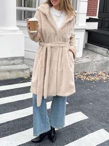 Manteau chic en fausse fourrure beige avec capuche et ceinture dans un style urbain