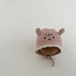 Detail of pink knit baby hat with animal ears embroidery and soft white ruffled edge