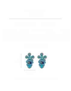 Detail view of blue knit flower earrings with shiny glass beads and silver needle base