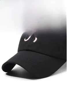 Détail d'une casquette de baseball noire avec broderie rose et surpiqûres sur la visière