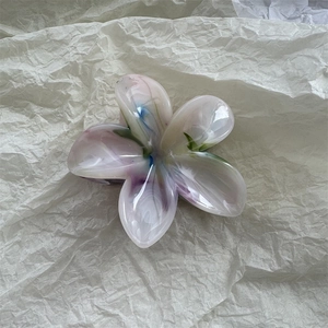 Detail shot of a translucent resin flower hair claw clip with colorful marble pattern