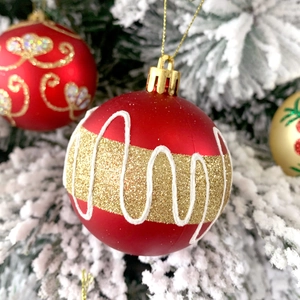 Dettaglio pallina di Natale rossa opaca con strisce dorate e una trama bianca a onde