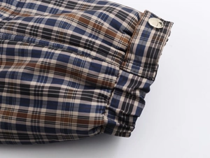 Detail view of plaid jacket sleeve with adjustable cuff and silver metal button