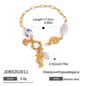 Detail of 18K gold plated ocean charm bracelet featuring seashells, pearls and seahorse