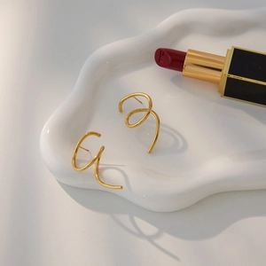 Macro shot of gold spiral titanium steel earrings on a textured ceramic jewelry tray