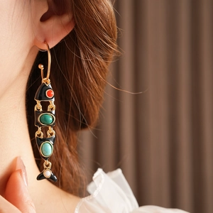 Close-up of vintage fish C-shaped enamel earrings with colorful gems on model