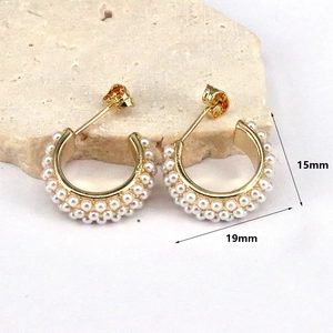 Detail view of C-shaped gold pearl earrings with dimensions 15mm height and 19mm width