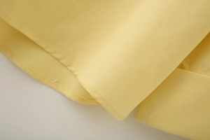 Detail shot of pale yellow linen blend fabric with neat stitching and smooth woven texture