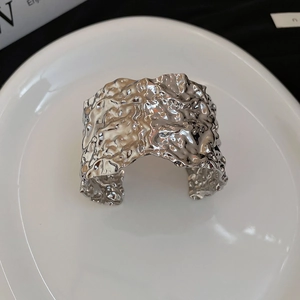 Detailed view of silver irregular wrinkled cuff bracelet with artistic liquid metal texture