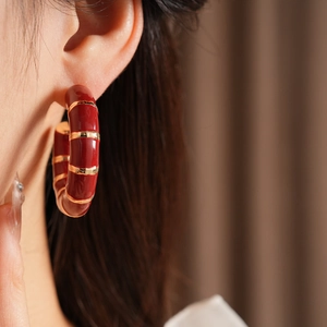 Close-up of vintage reddish-brown enamel C-shape hoop earring worn on model ear
