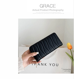 Detail of a black long PU leather wallet with vertical wave quilting and gold zipper closure