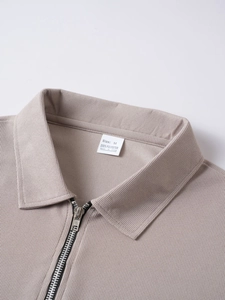 Macro shot of khaki waffle knit texture and half-zipper collar on men's polo shirt