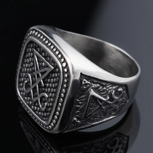 Macro shot of silver stainless steel Lucifer sigil ring on a dark reflective surface